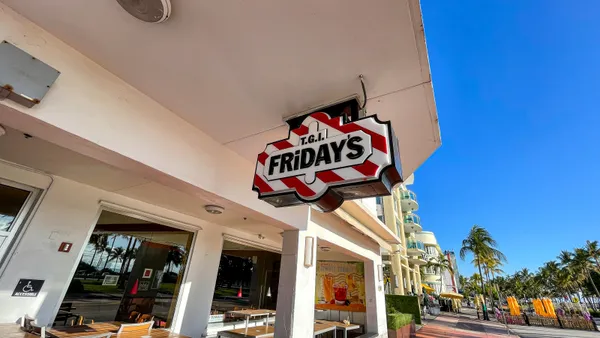 A restaurant sign on an Art Deco building. The restaurant is empty, the sky beside the sign is a cold, harsh blue.