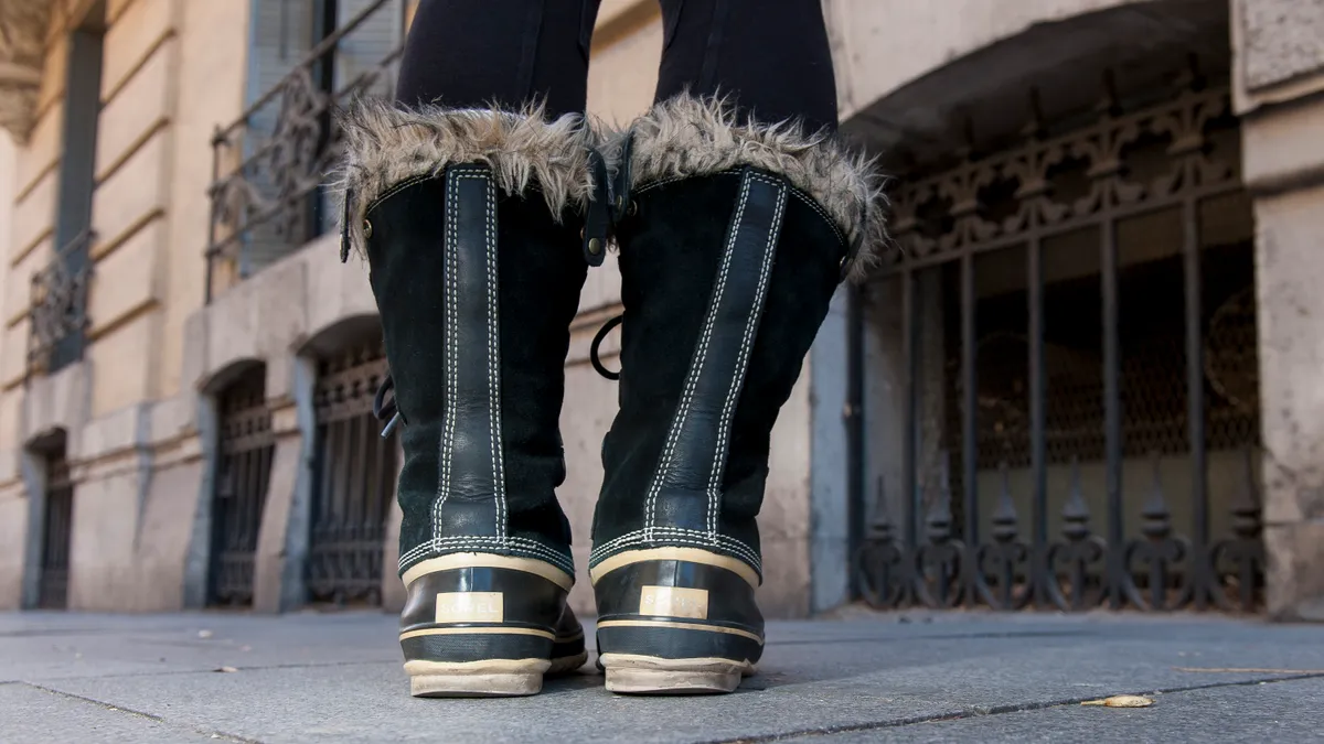 A closeup of a person wearing a pair of fur-trimmed boots.