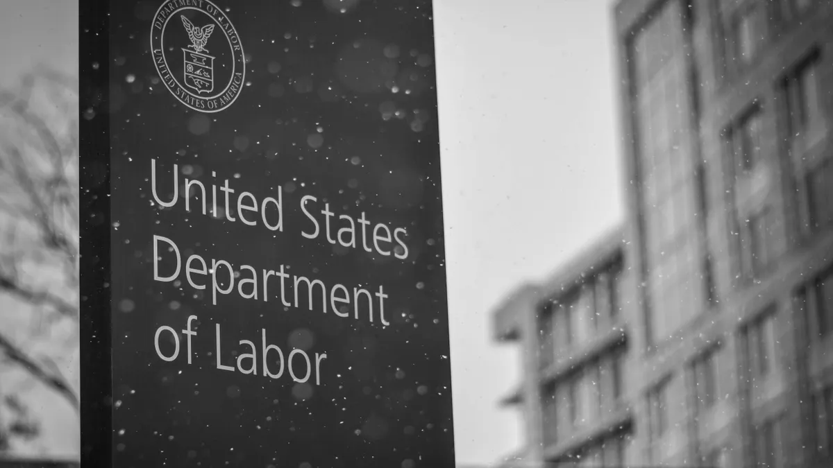 A black and white photograph of the US Department of Labor's sign, with its insignia.