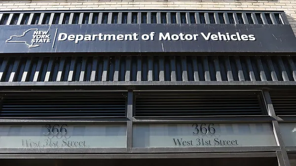 A logo and branding of the New York State Department of Motor Vehicles on the side of a building in New York City.