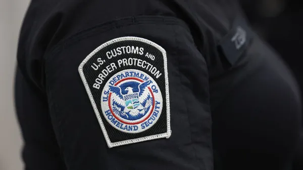 A U.S. Customs and Border Protection badge is displayed on a sleeve.