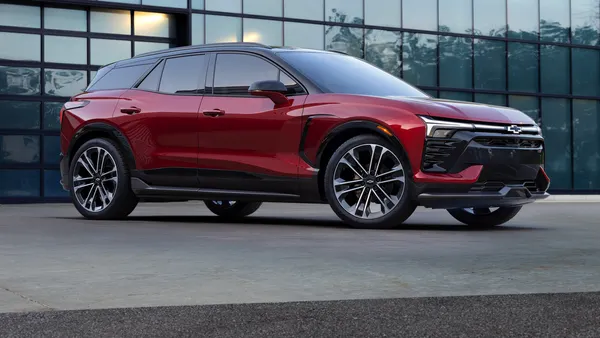 The passenger’s side view of 2024 Chevrolet Blazer EV SS in Radiant Red parked outdoors in front of a building.