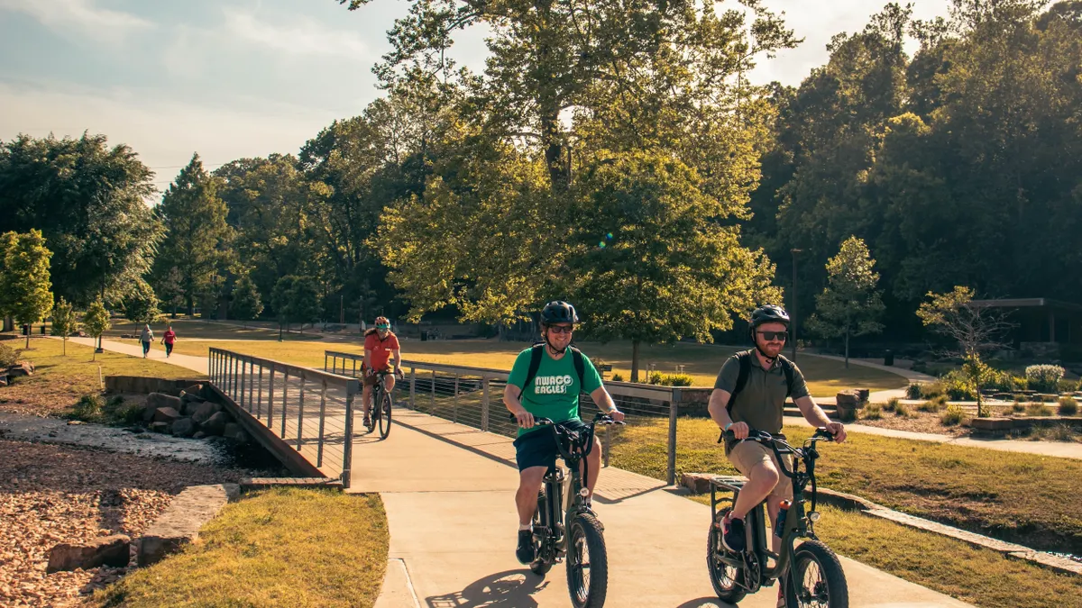 People riding bicycles on a path over a bridge.