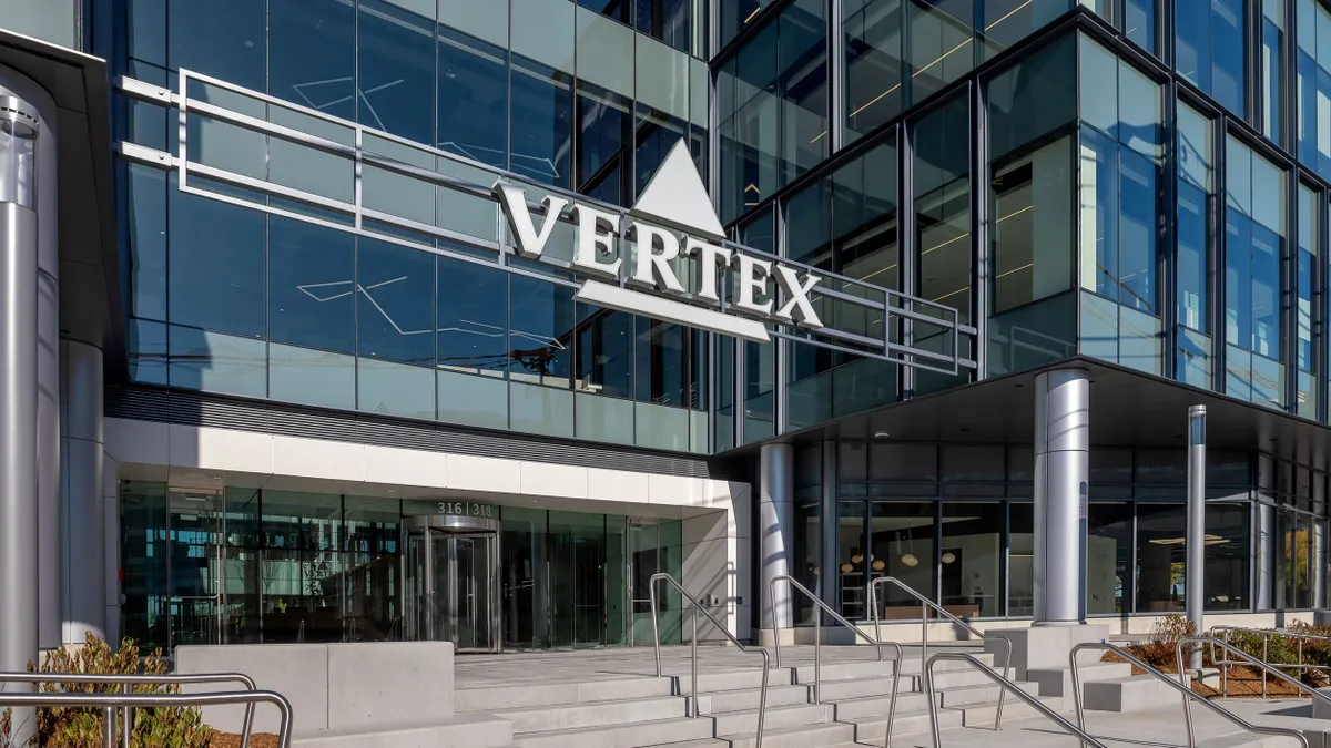 A sign spelling Vertex hangs over an office building entrance.