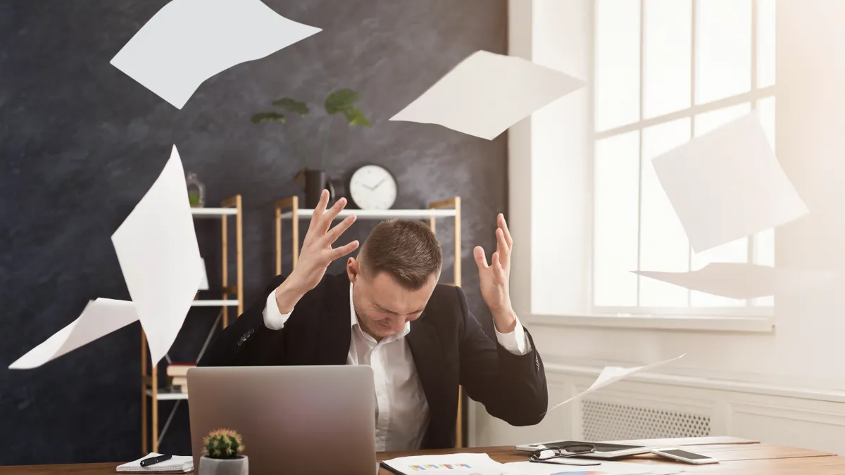 A stressed out lawyer sitting at his desk after throwing papers in the air