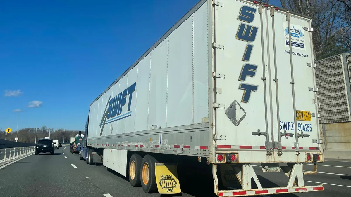 Swift trailer hauled on a highway alongside traffic.