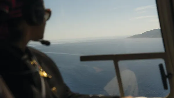 A man flys a plane over a body of water.