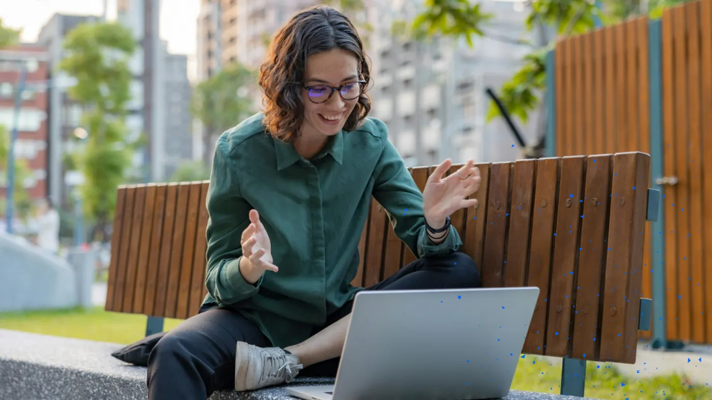 Person reacting happily to something on laptop while in a park.