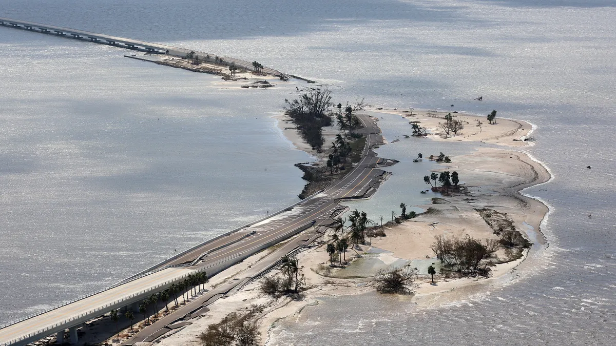 Aerial view of a long curved flat bridge that's partly underwater.