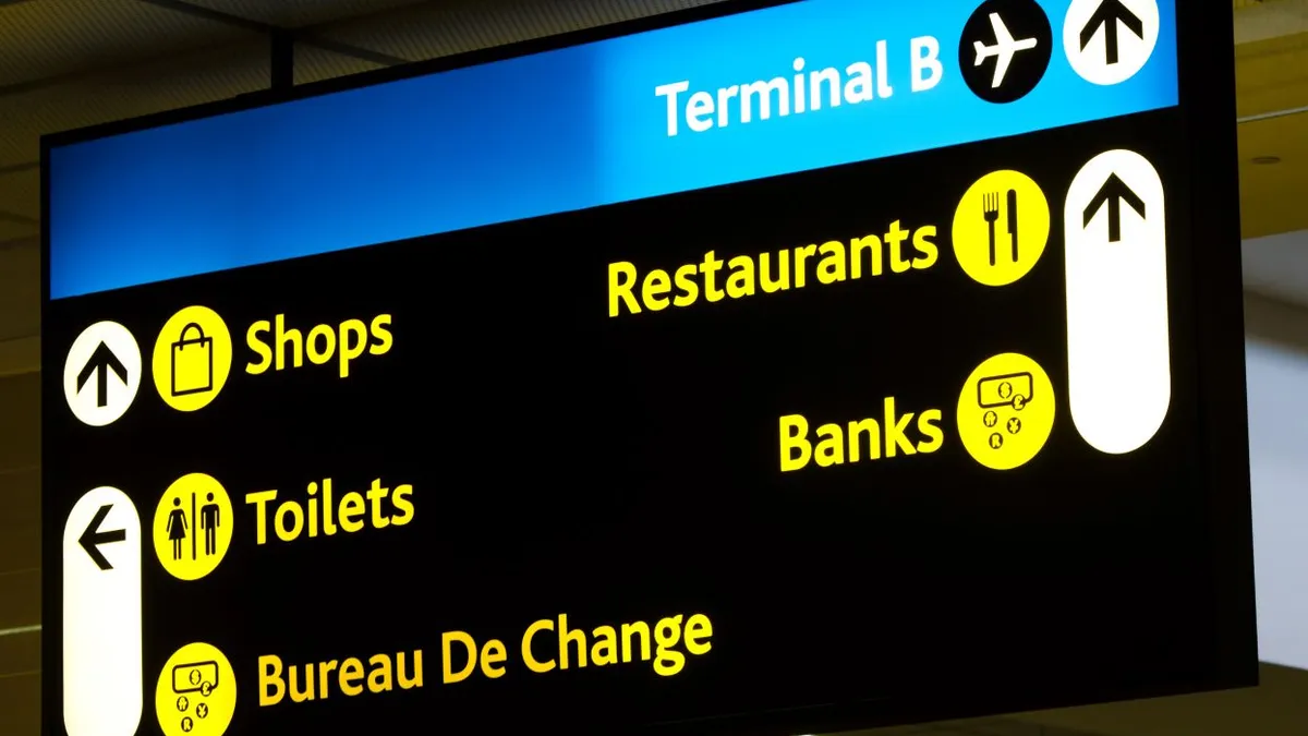 An image of an airport sign that says Terminal B with a restaurant sign highlighted in the foreground.