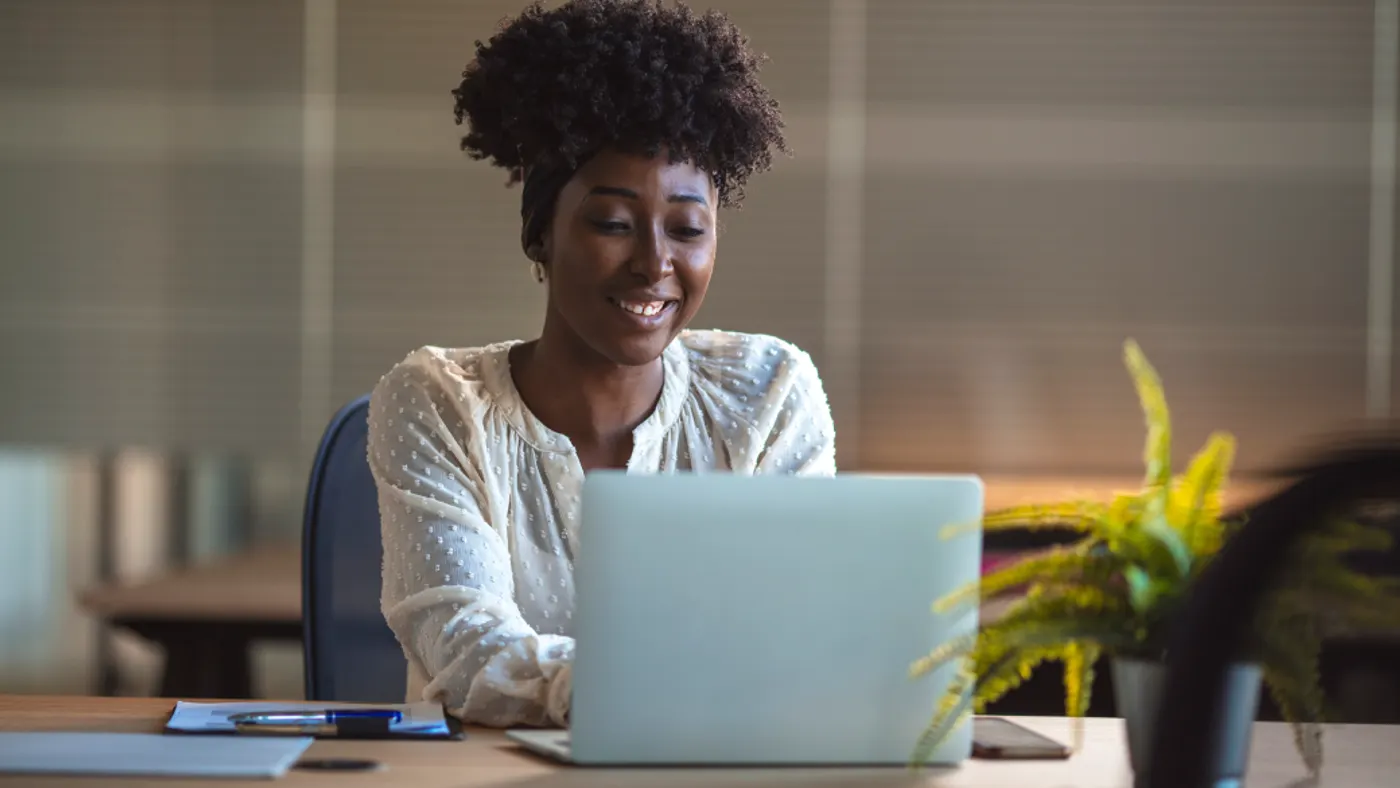 Young black woman in an office smiling to camera, close up. Portrait of young black woman in creative office.
