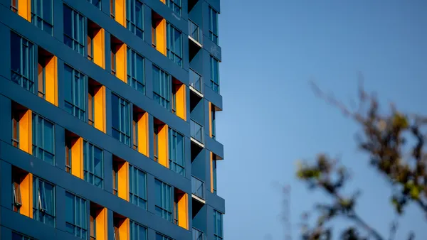 A blue apartment building with orange-accented windows.