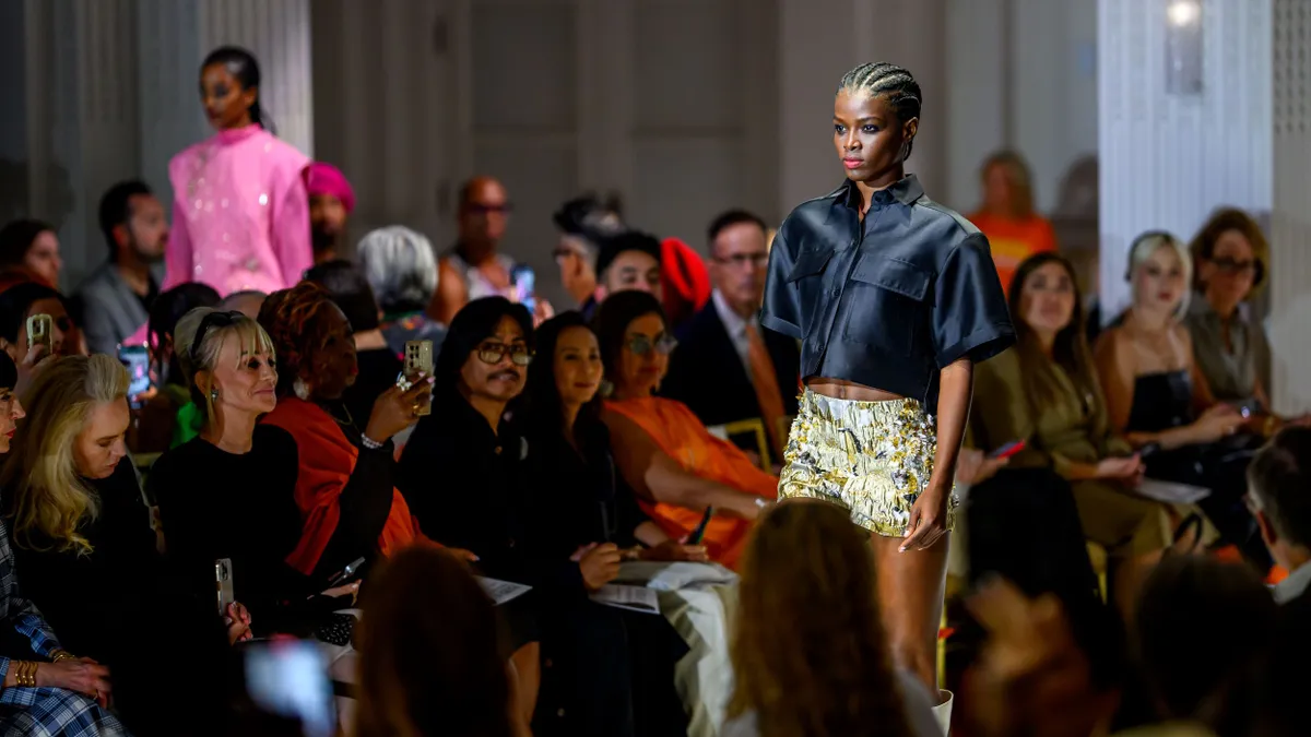 Models walk parallel runways surrounded by onlookers.