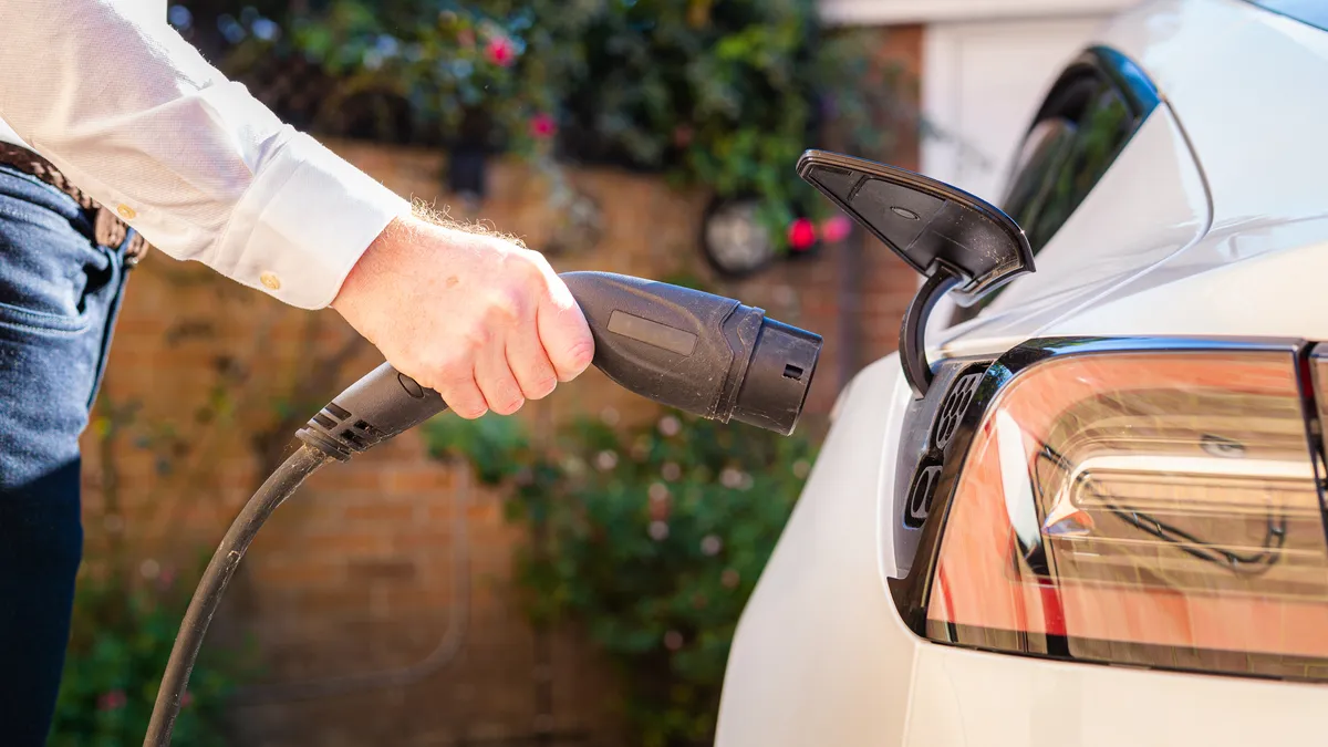 Person holding up EV charger to car