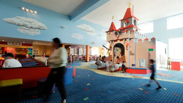 Children play in a lego castle in a brightly colored room.