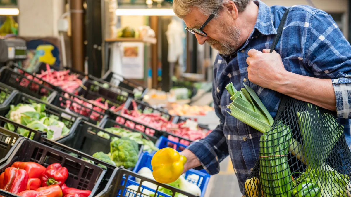 Customer shopping for produce with a reusable bag