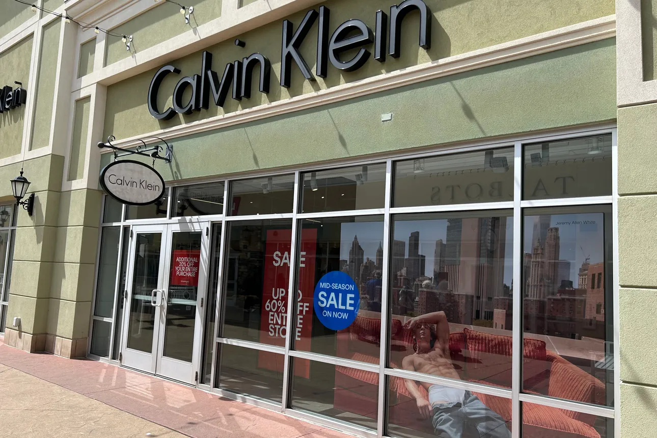 The exterior of a Calvin Klein store. The windows show signs for sales and an image of actor Jeremy Allen White wearing Calvin Klein underwear.