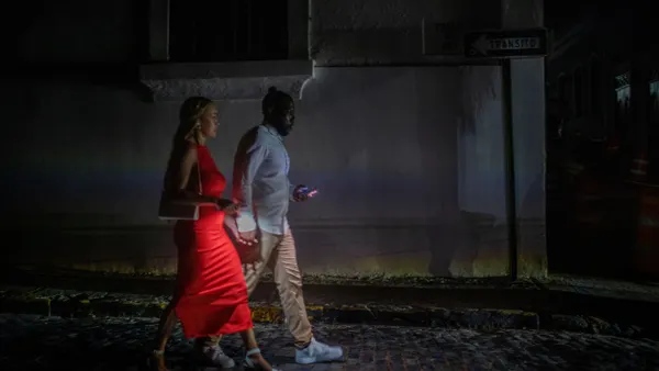 A tourist couple use their phones to light the streets during a power outage