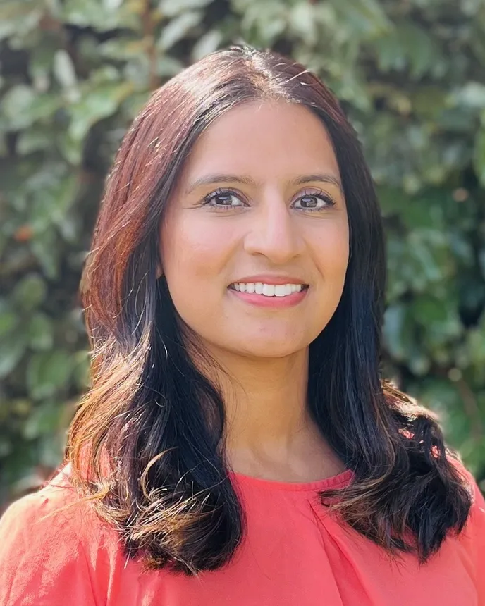 Headshot of a woman with long dark hair and a coral colored top.