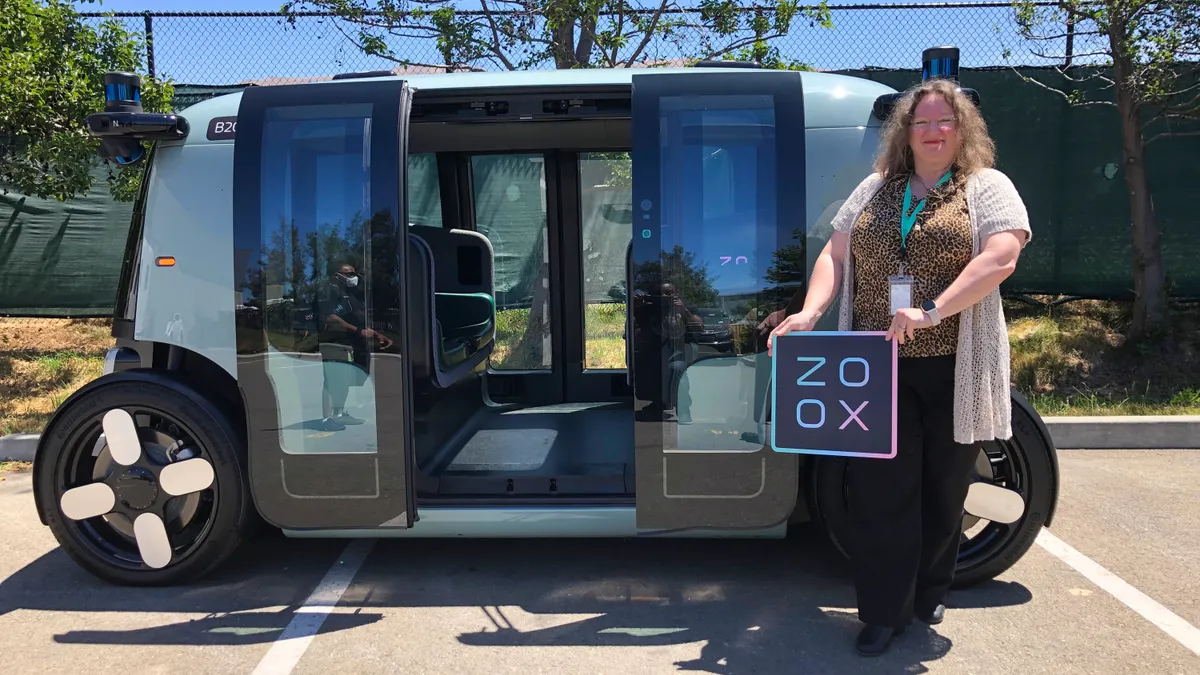 Worker stands with a Zoox robotaxi