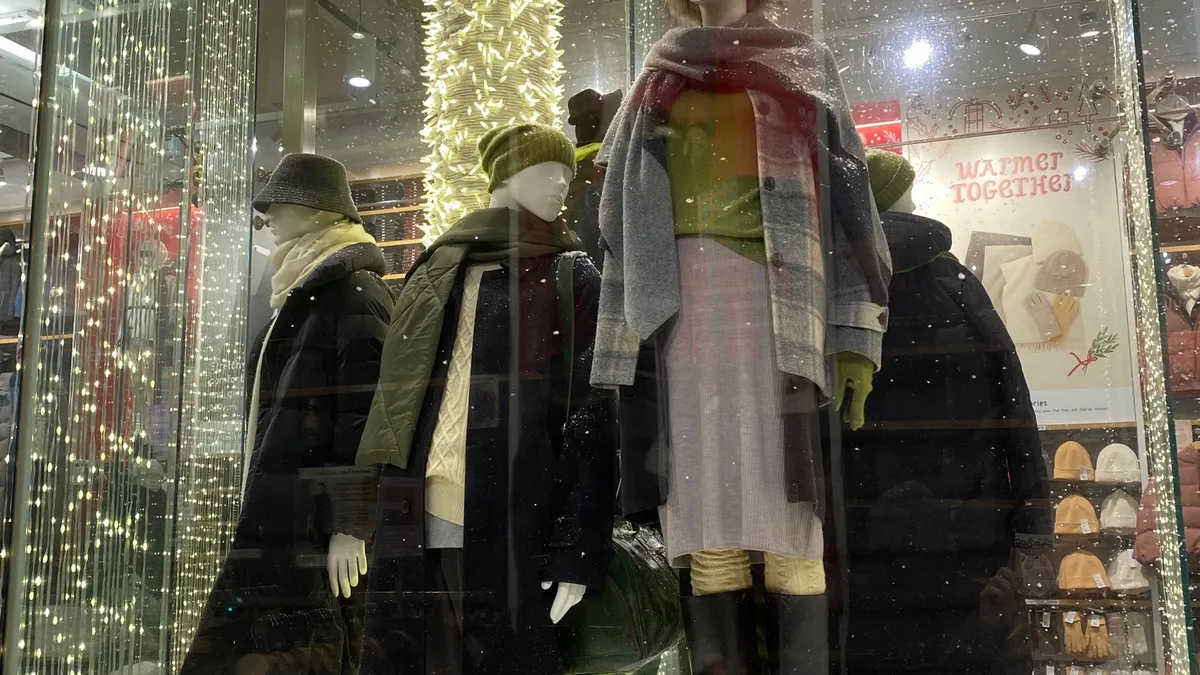 Mannequins grouped together wearing winter clothes in fake snow.