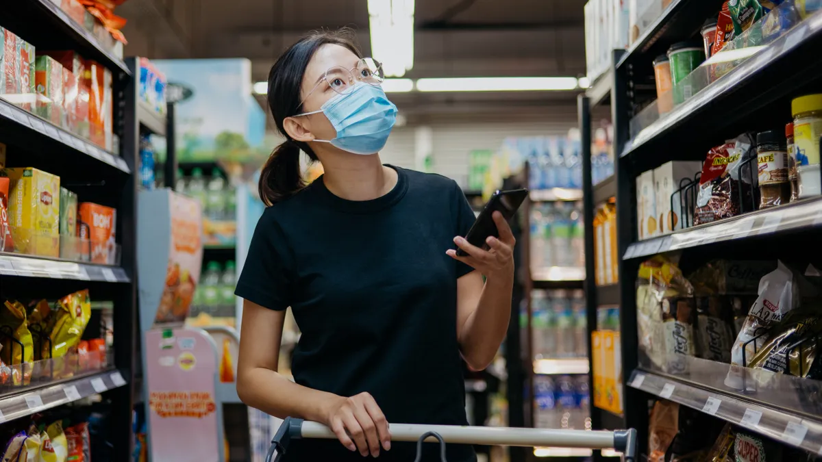 Image of an Asian Chinese woman wearing protective face mask shopping for groceries in supermarket