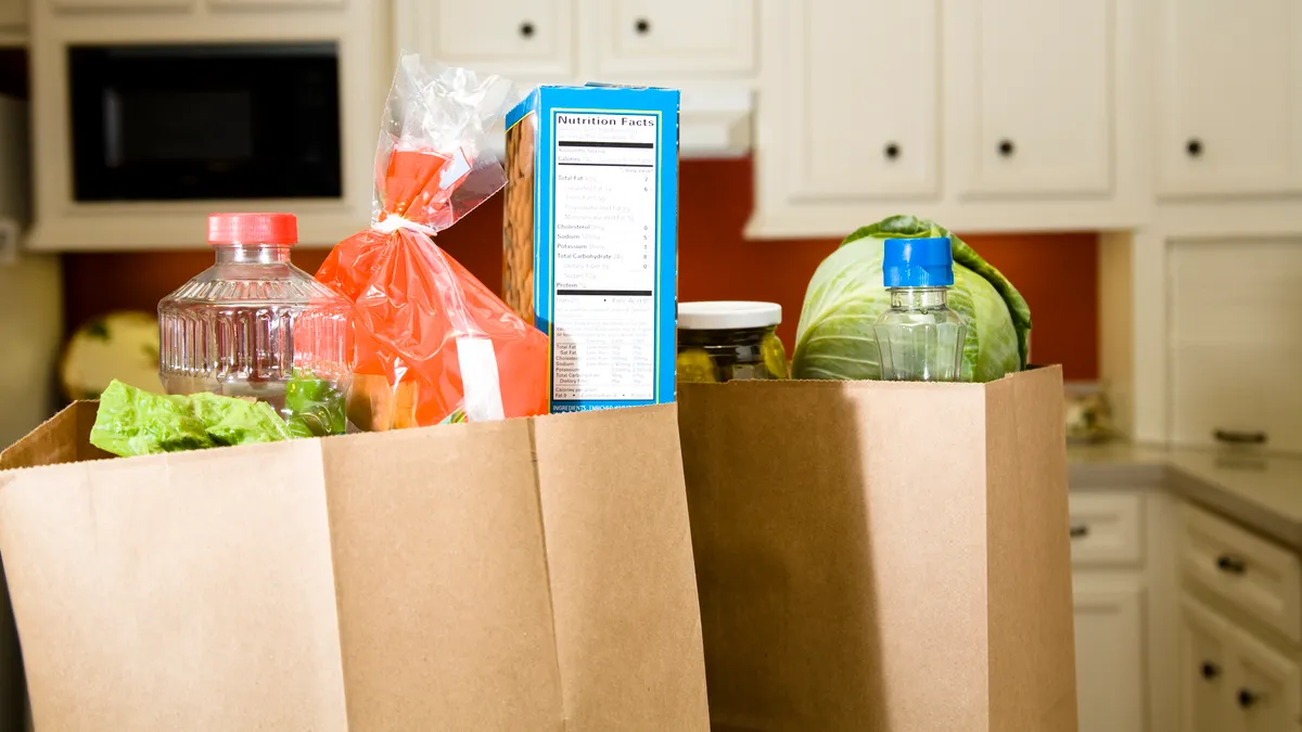 Two paper bags full of groceries sitting on a kitchen counter