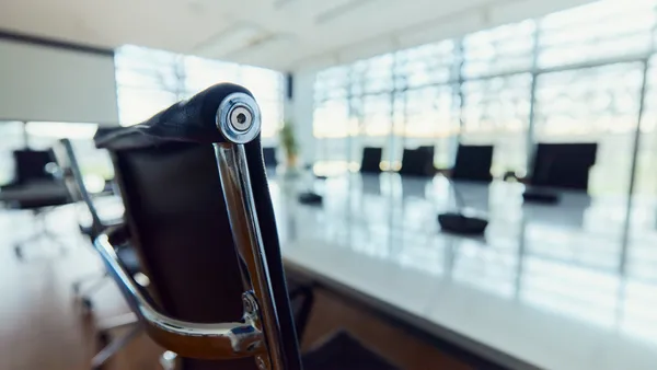 A black office chair is pushed against a conference table in meeting room.