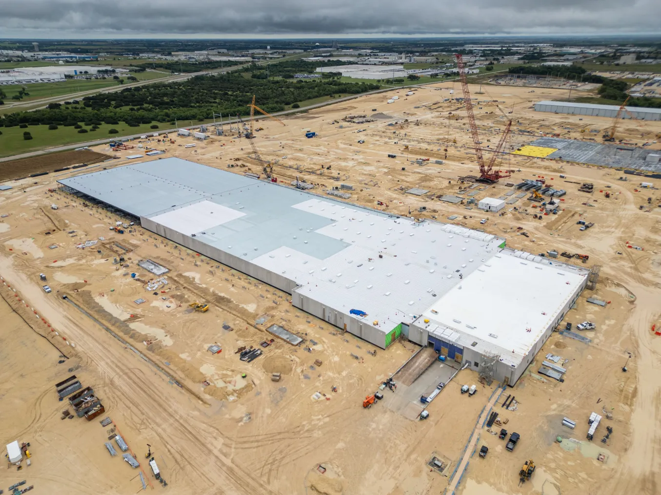 An aerial view of a construction site with cranes and construction vehicles.