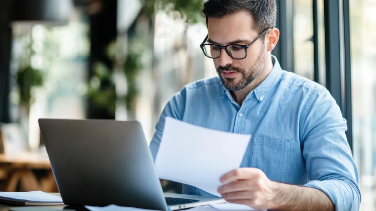 Man working at laptop with papers