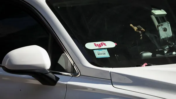 A Lyft logo is displayed on a vehicle driving through Times Square.