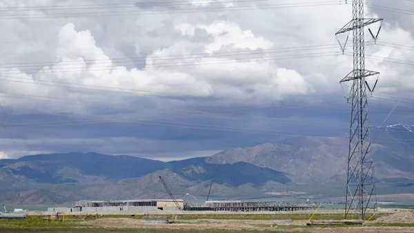 An electric power line runs near a building that is under construction.