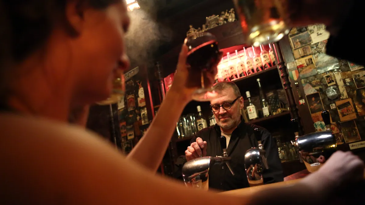 a bartender pours a pint of beer.