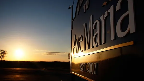 A sign for the community of Ave Maria, Florida, with the sun in the background.