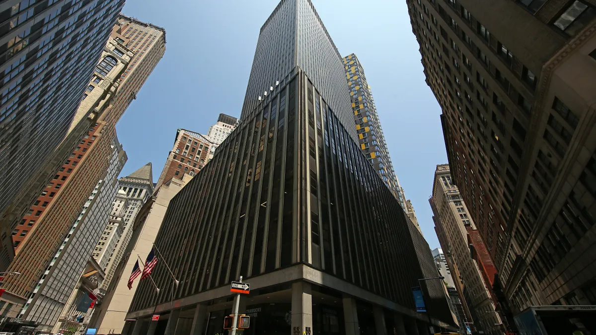 A view of an office building from below, surrounded by other tall towers.