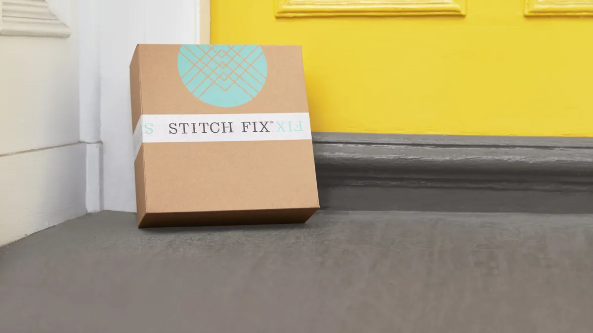 A cardboard box with a round light-blue logo and the words "Stitch Fix" leans against a bright yellow door.