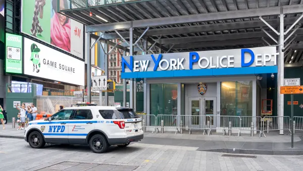 A white car that says NYPD in front of a building with the words New York Police Department.