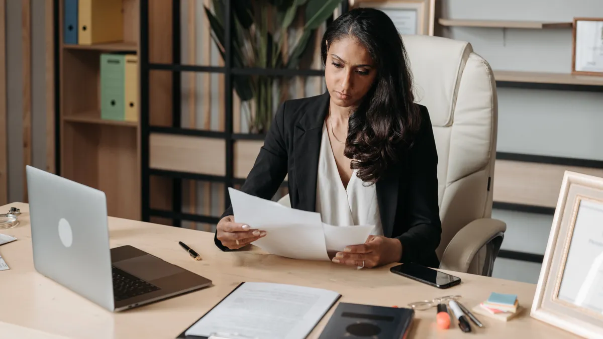 Serious employee sits at the desk and reads over paperwork