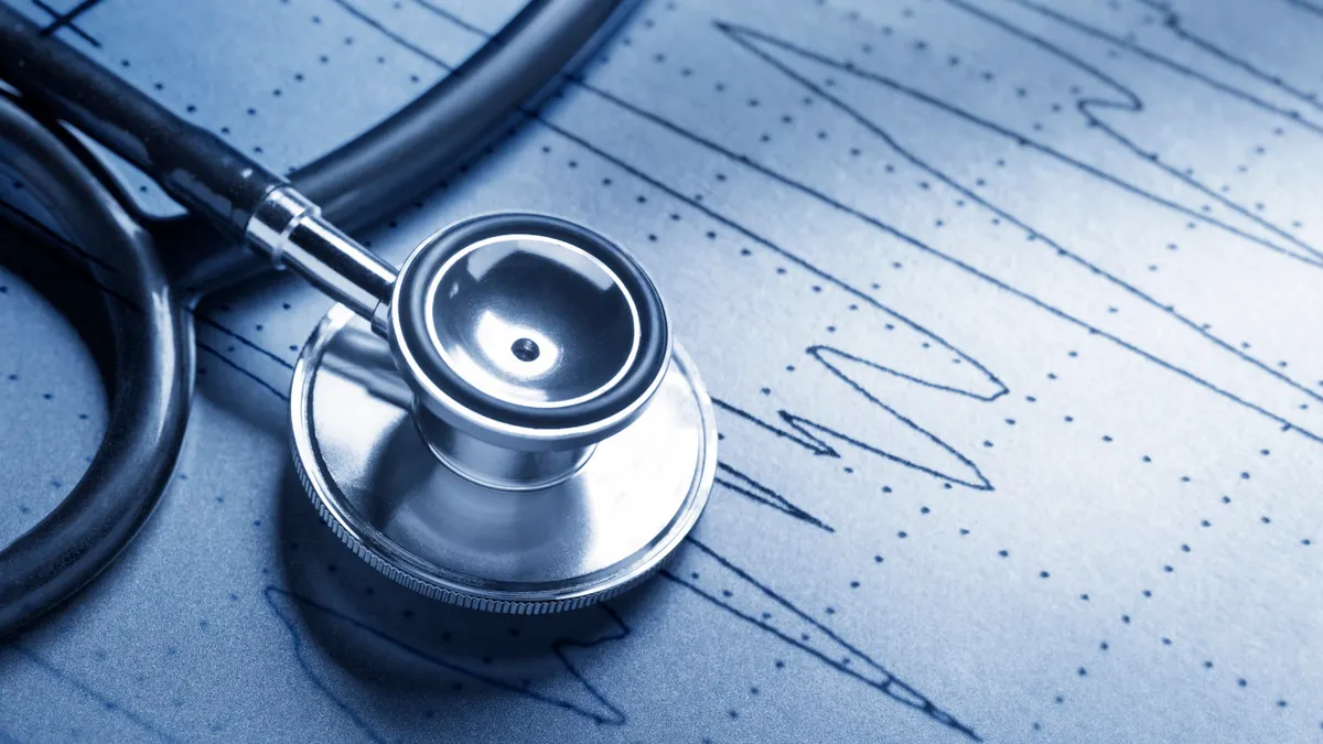 A stethoscope rests on top of an EKG printout. A cool blue cast dominates the scene.