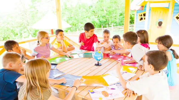 Group of elementary school children having class in the outdoor classroom and looking at the globe.