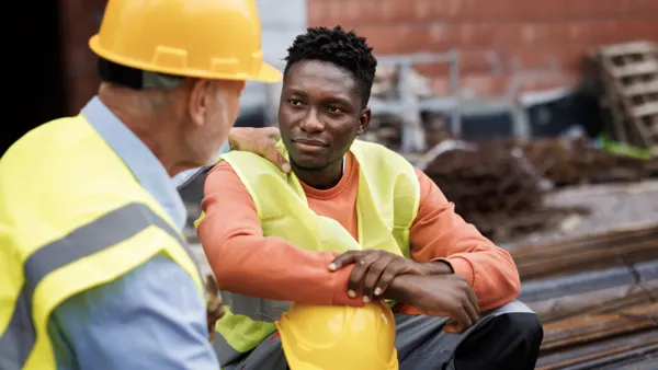 Senior man consoling his colleague at construction site.