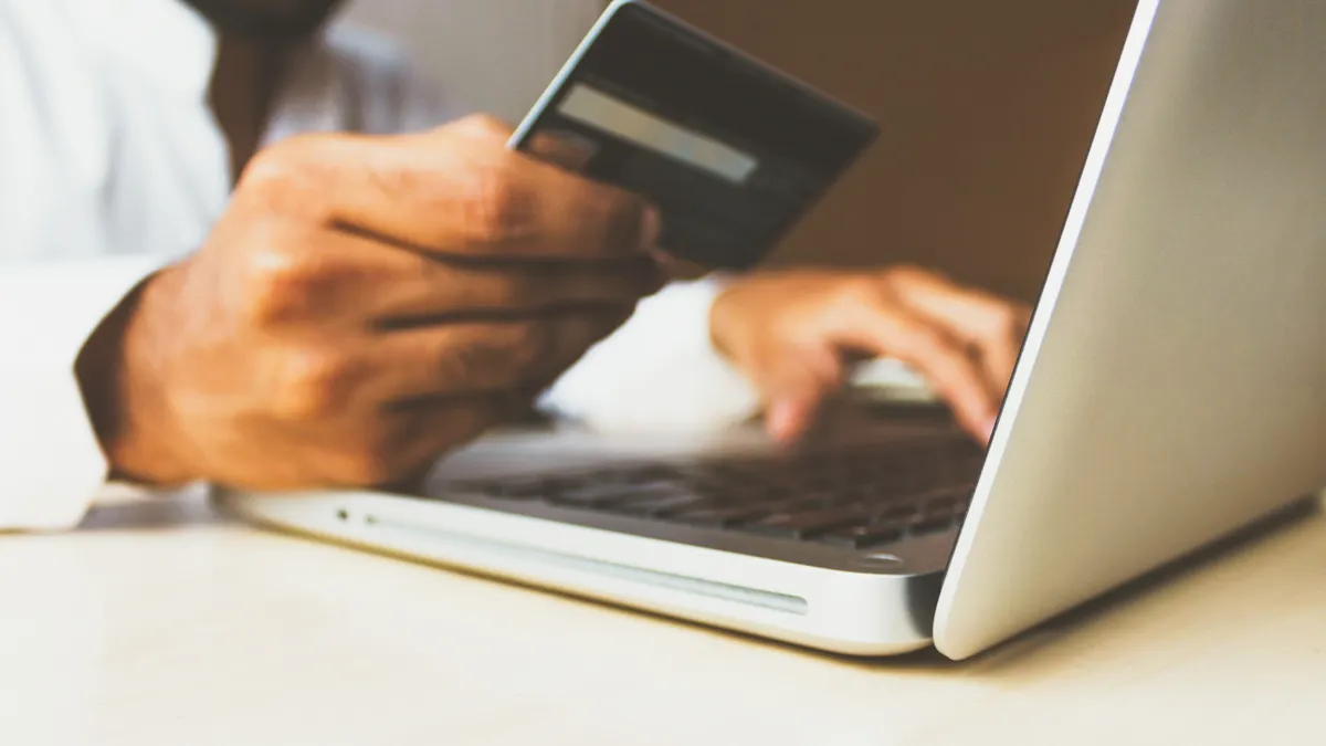 person looking at credit card and laptop