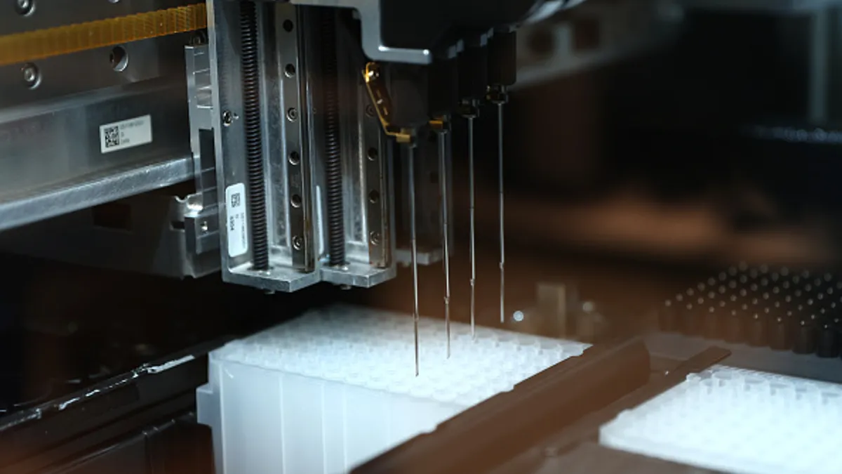 A machine moves between several rows of test tubes.