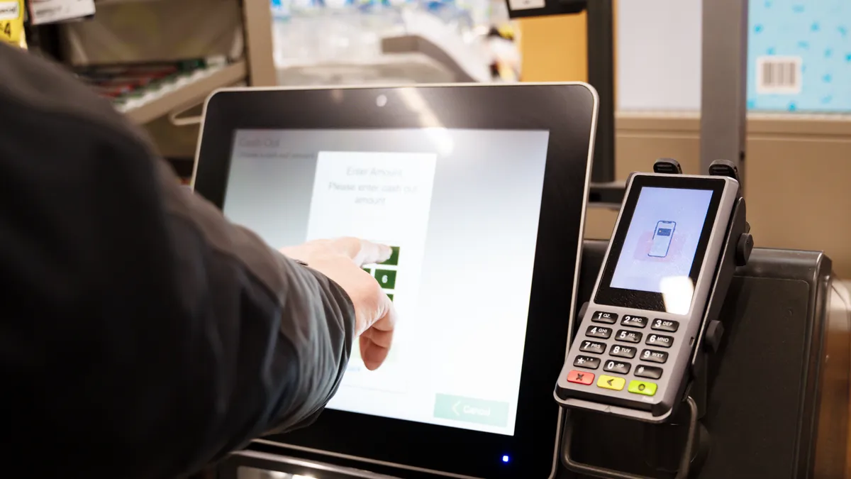 Close-up of a person using a self checkout machine.