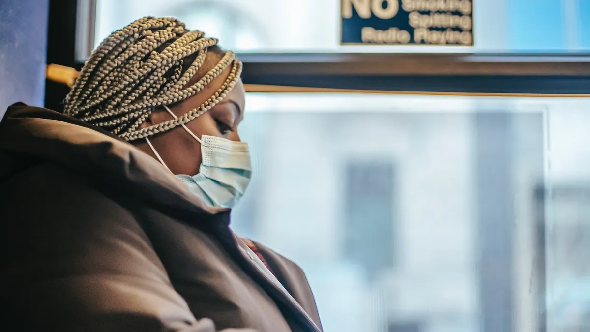 woman rides a bus wearing a facemask