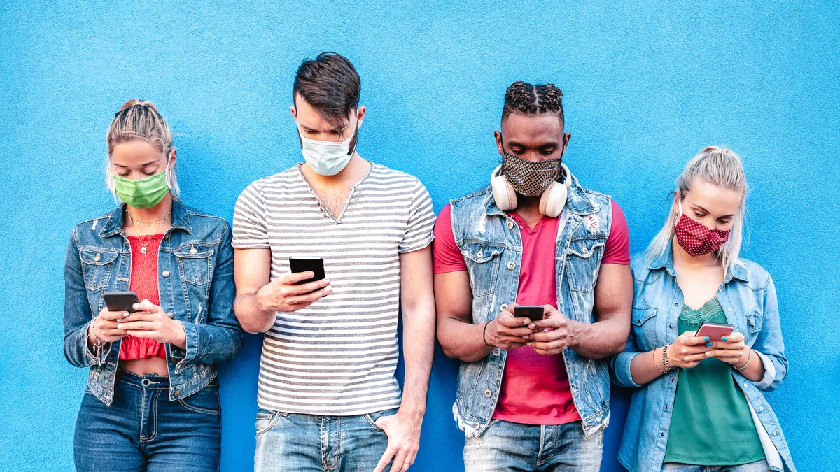 Multiracial friends with face masks using tracking app with mobile smart phones.