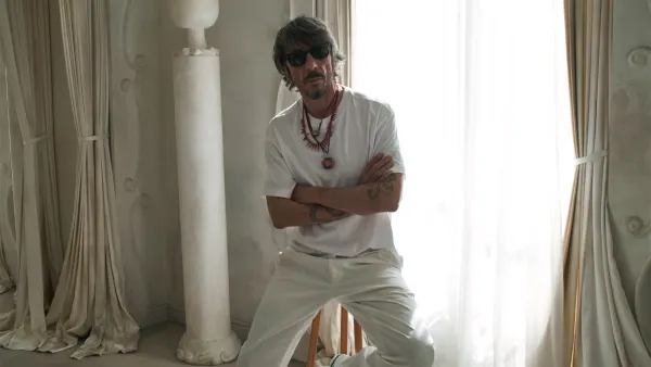 Pierpaolo Piccioli is seated in a room with window lighting on a stool.