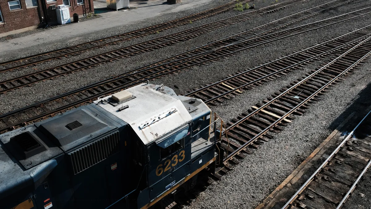 The front of a train is visible as it sits on rail tracks