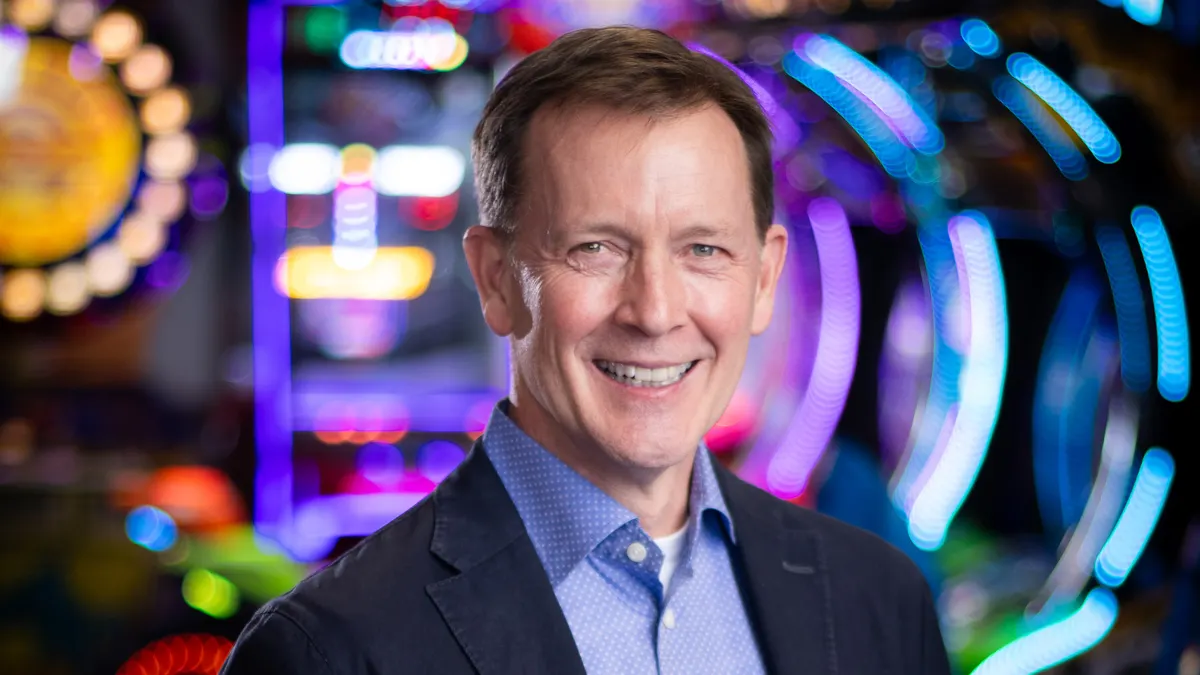 An image of a person in a suit standing in front of blurred arcade games.