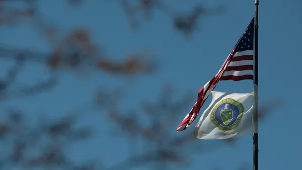 A U.S. flag and the flag of the U.S. Department of Energy fly outside its building.